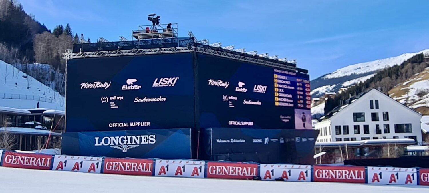 Ski race finish area with big screen showing Liski Sport Equipment as official supplier